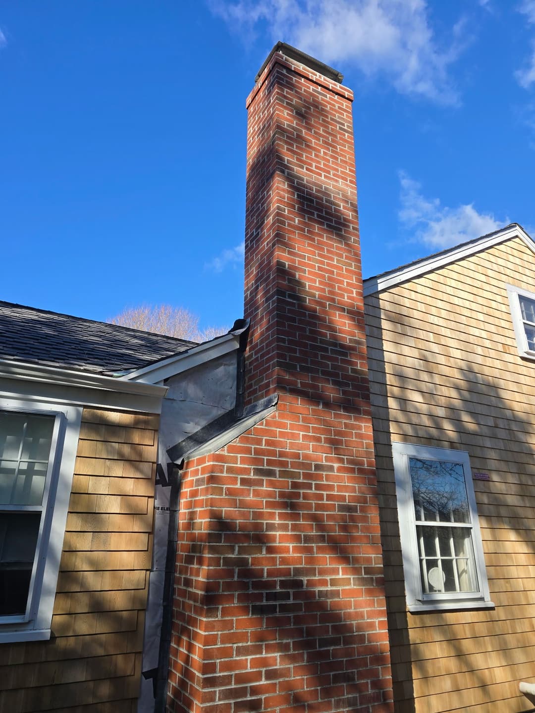 Brick chimney against a clear blue sky, showcasing traditional architecture and detailed craftsmanship.