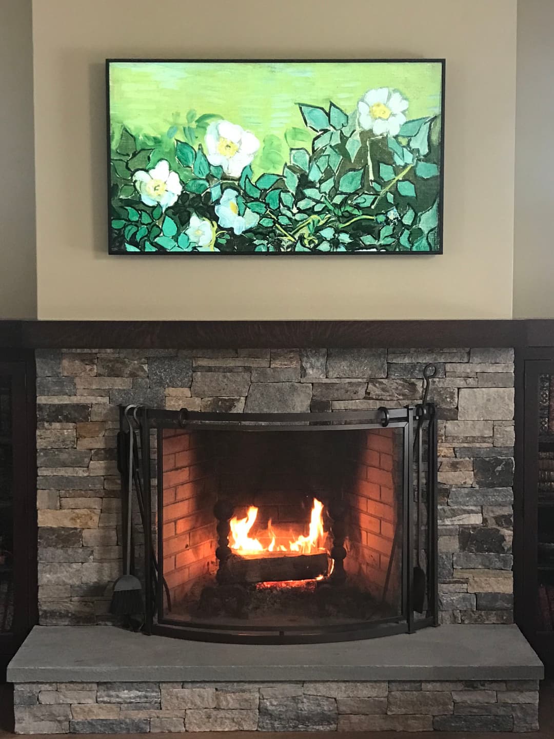 Cozy living room with a stone fireplace and a floral painting above the mantle.
