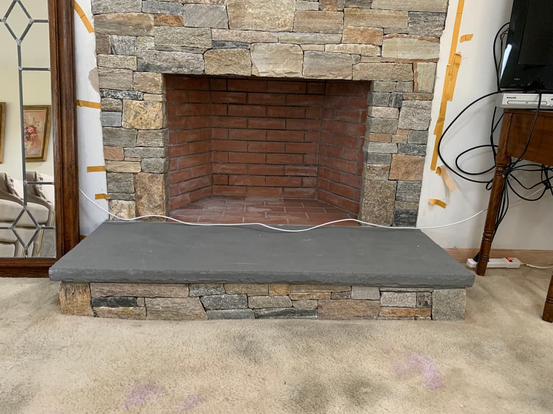 Stone fireplace with a brick interior and a slate hearth, set in a remodeled room.