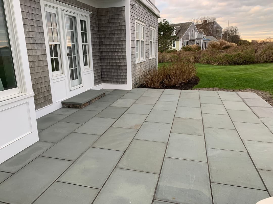 Patio featuring large slate tiles with landscaped garden and house in the background.