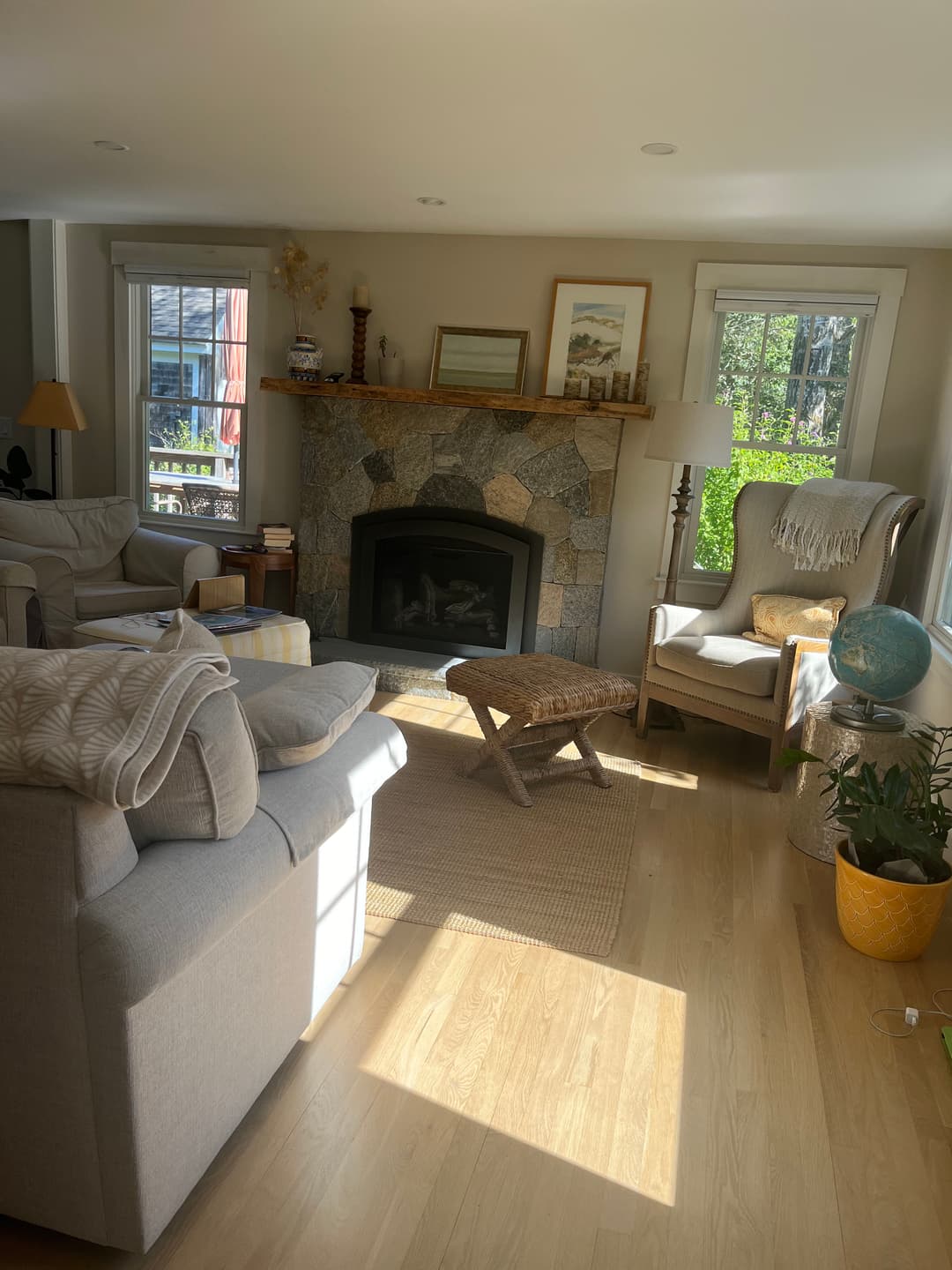 Cozy living room with natural light, stone fireplace, and comfortable seating.