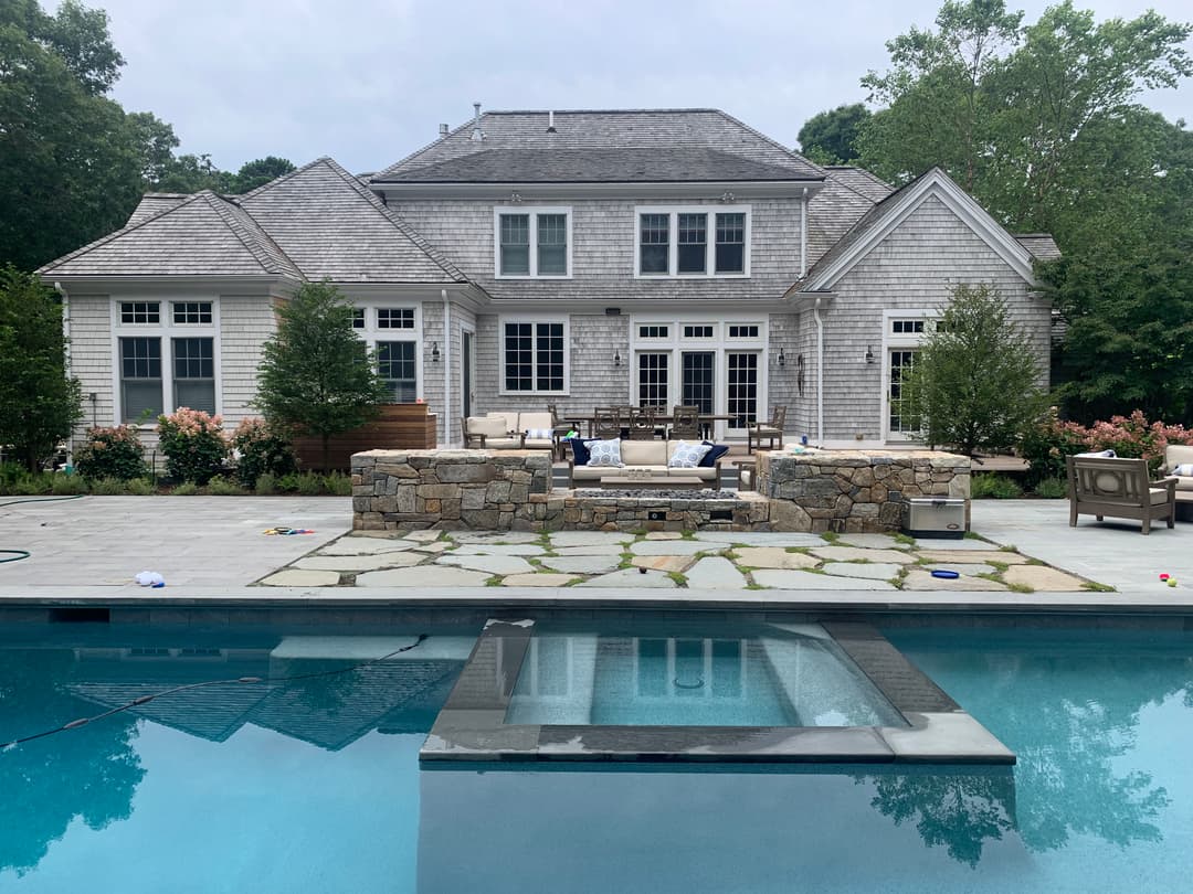 Luxury home with pool and outdoor seating in a landscaped backyard setting.