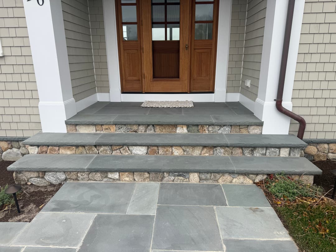 Front entrance with stone steps, slate flooring, and wooden double doors.
