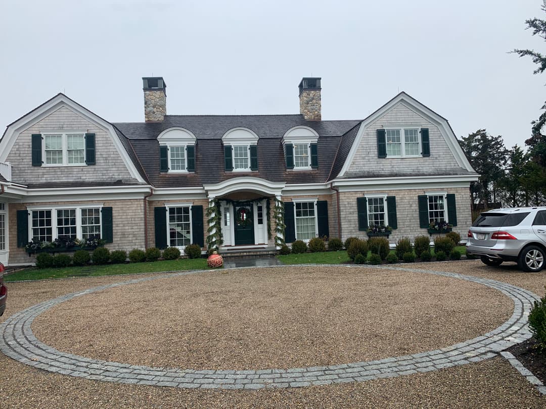 Elegant residential home with a landscaped circular driveway and festive holiday decor.