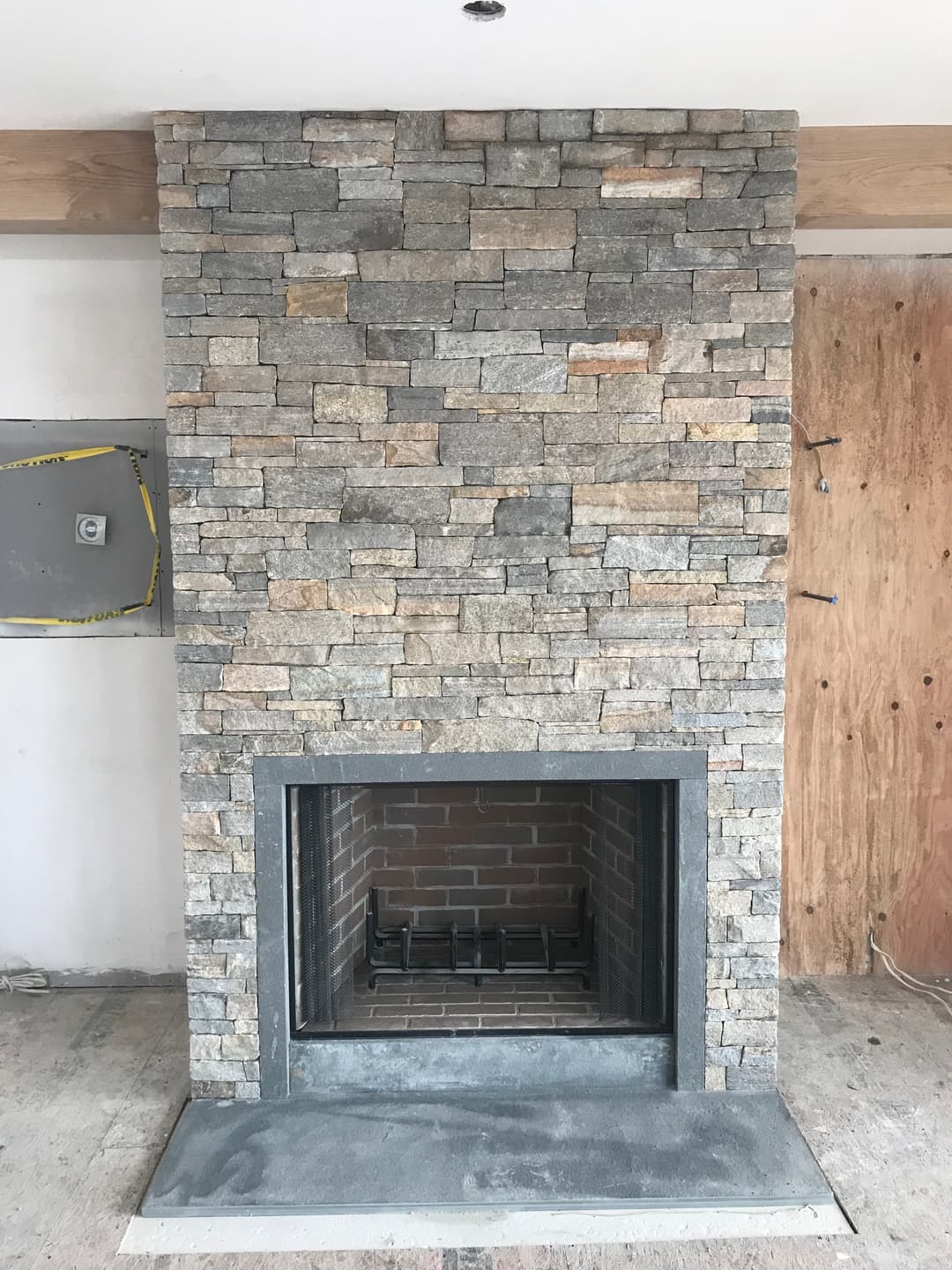 Modern stone fireplace with a sleek design and rustic brick interior in a minimalist room.