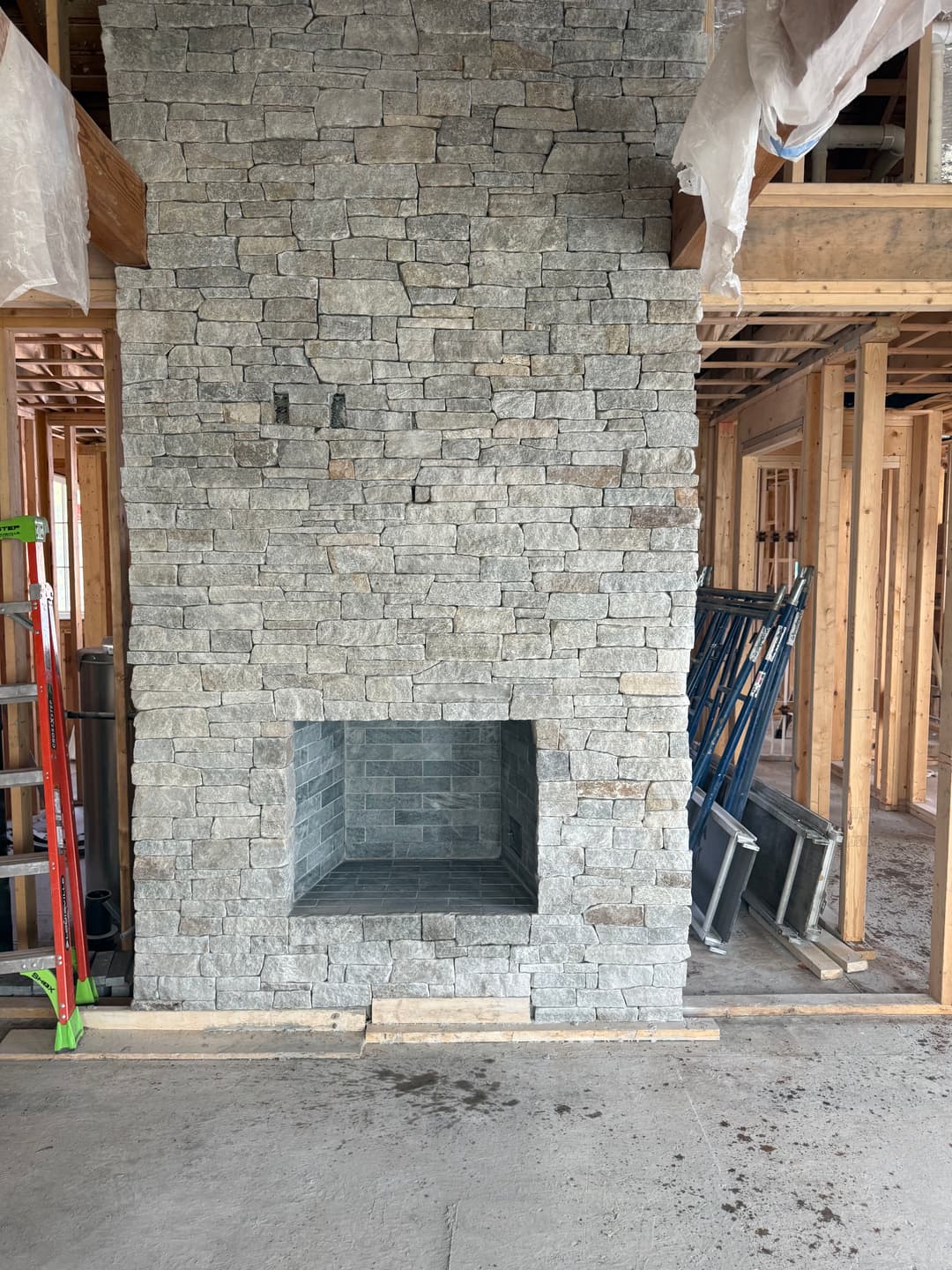 Stone fireplace under construction with wooden framing in a home interior.