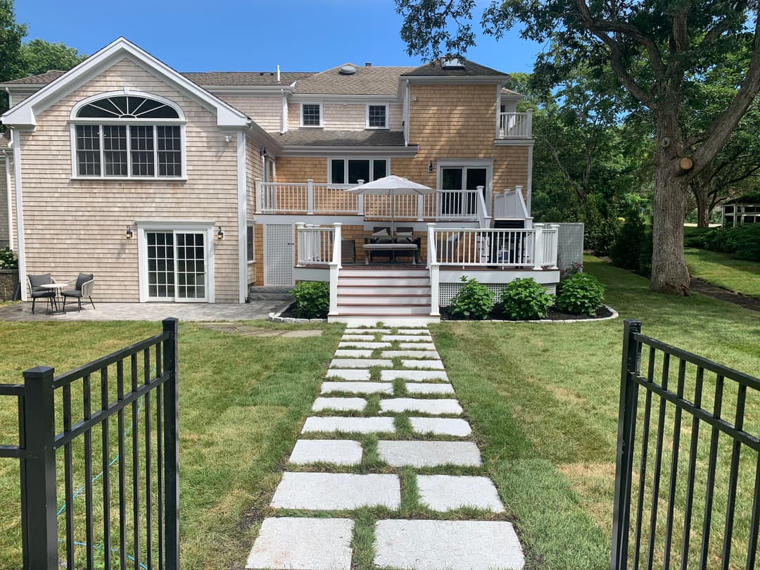 Modern backyard with stone pathway leading to a stylish home deck and patio in a serene setting.