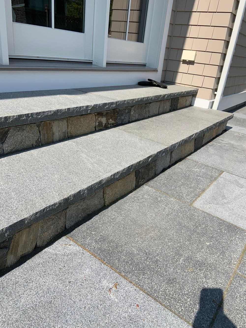 Granite stone steps with a mix of smooth and textured surfaces leading to a home entrance.