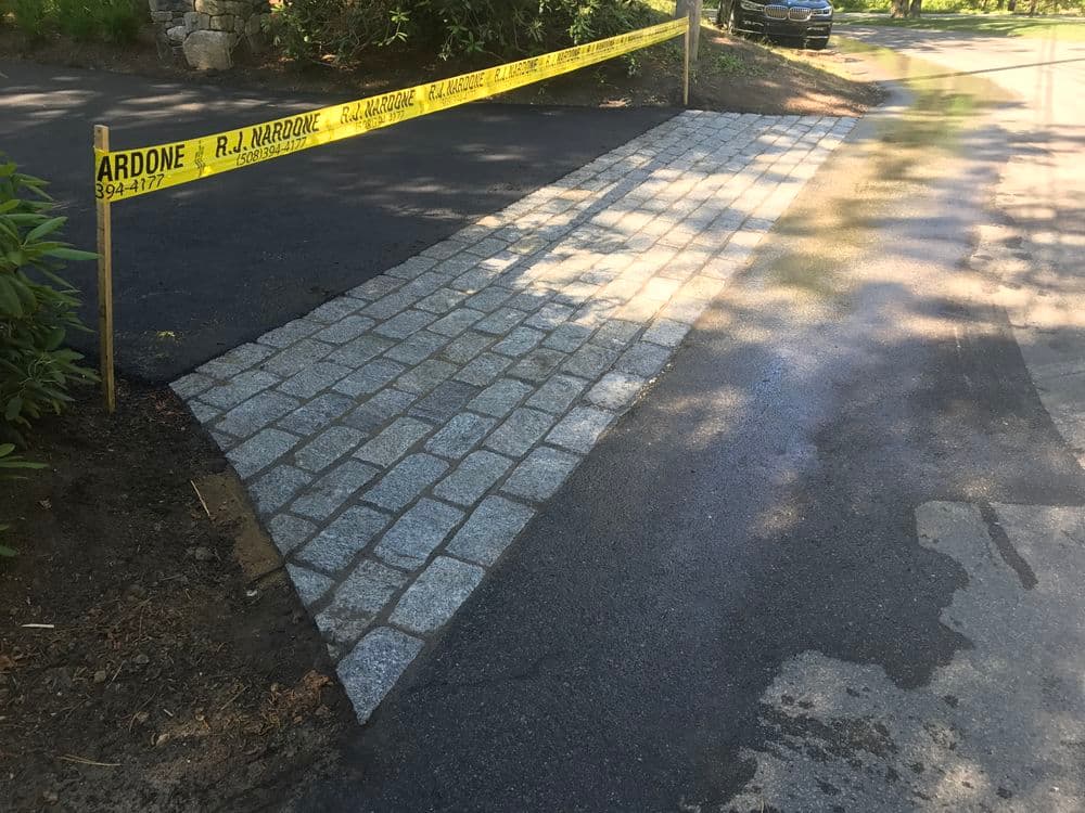 Newly paved cobblestone pathway with caution tape, showcasing quality craftsmanship.
