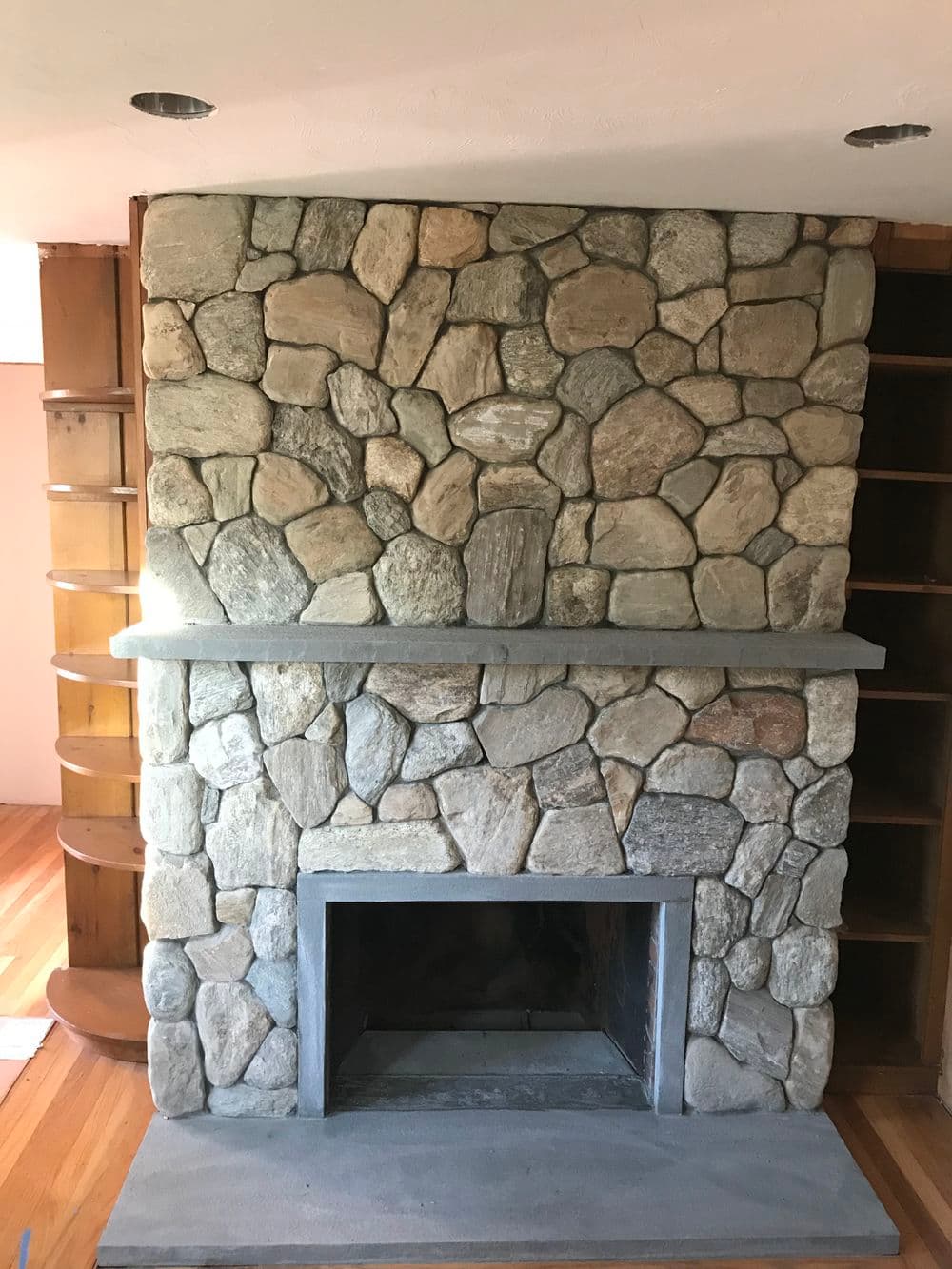 Stunning stone fireplace with rustic design, featuring natural stones and a sleek mantel.