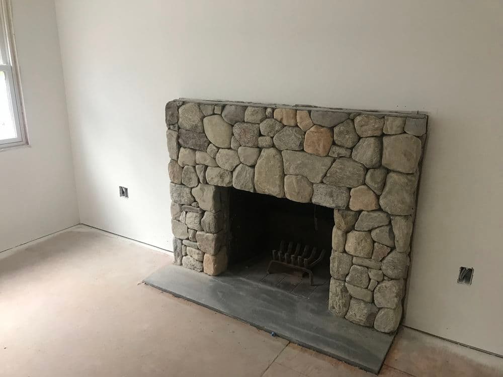 Stone fireplace in a room with unfinished walls and floor, ideal for home design inspiration.