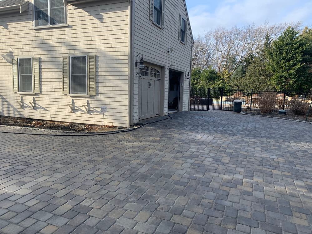 Paved driveway and home exterior with landscaped yard and fence.