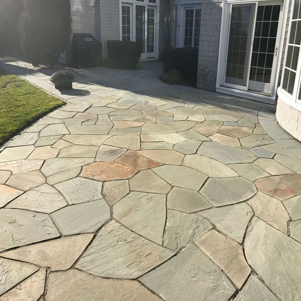 Natural stone patio with irregular flagstone pattern in a backyard setting.