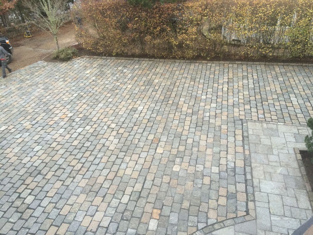 Paved stone driveway with an elegant design and surrounding autumn foliage.