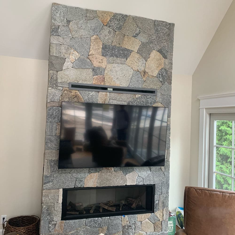 Modern stone fireplace wall with mounted TV, featuring natural stone design and cozy ambiance.