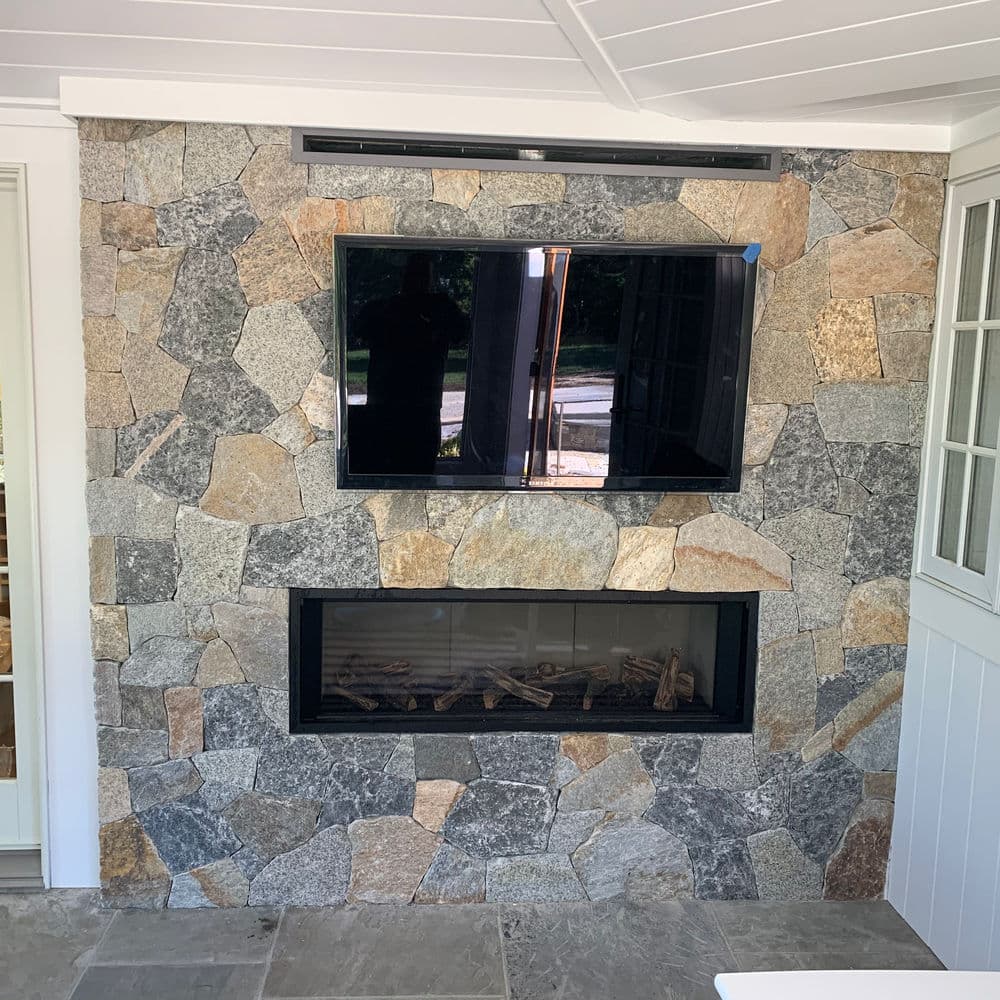 Modern stone fireplace with gas insert and mounted flat-screen TV in a stylish living space.