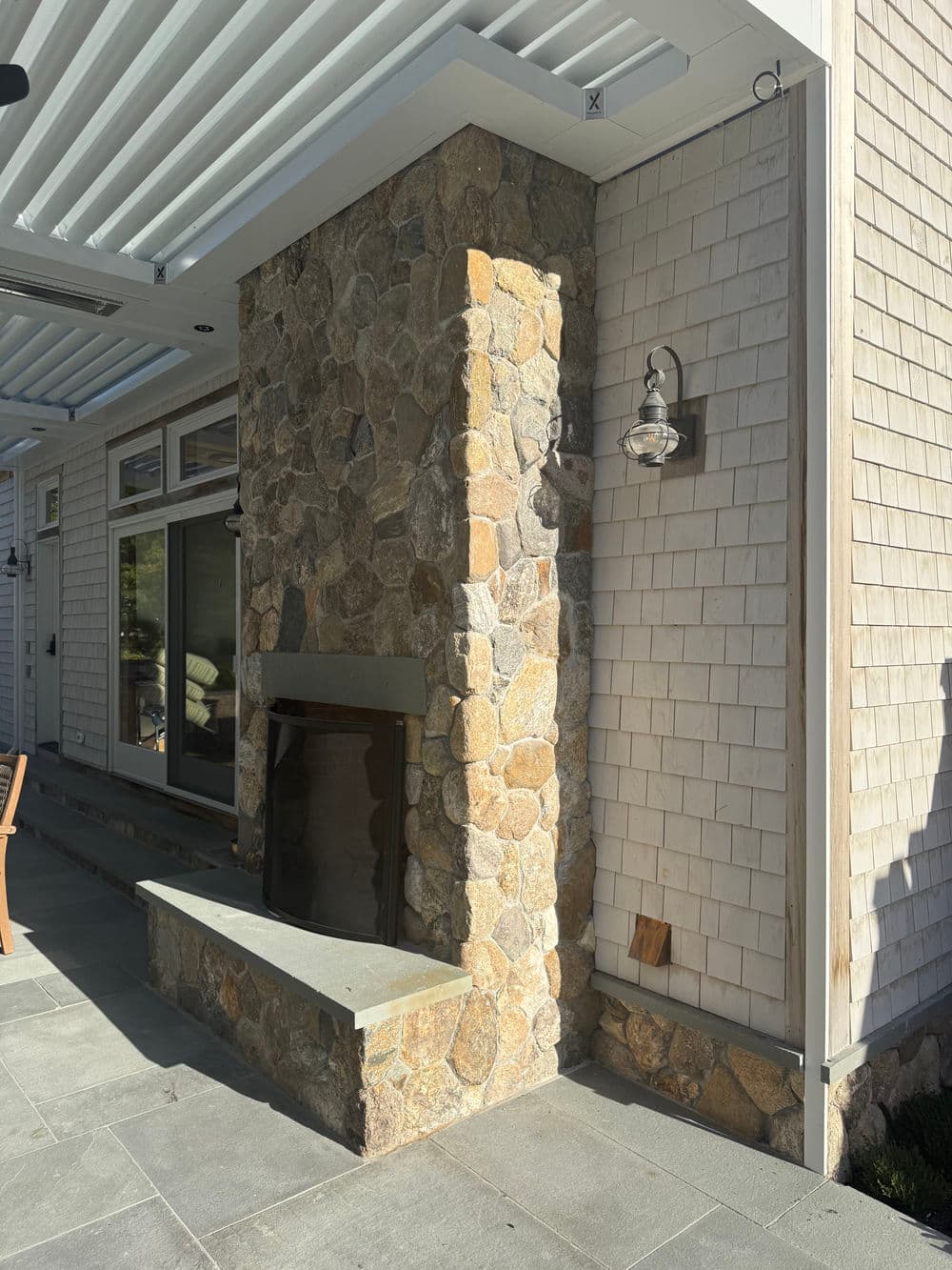 Modern outdoor stone fireplace with gray stone exterior and stylish wall sconces.