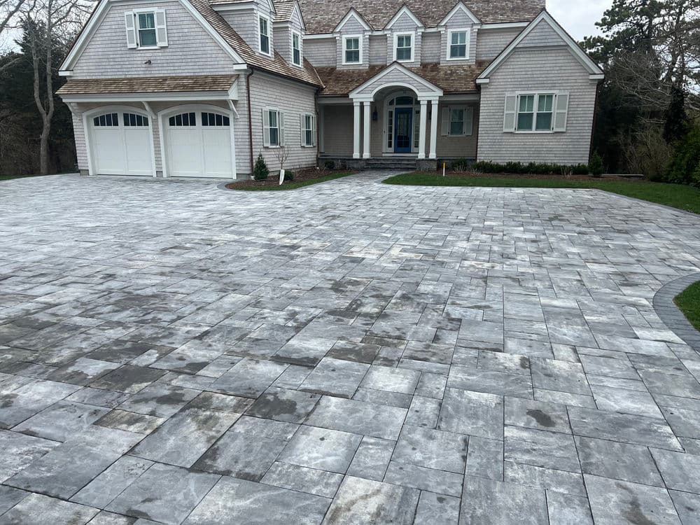 Modern home with gray paver driveway and landscaped yard in a suburban setting.
