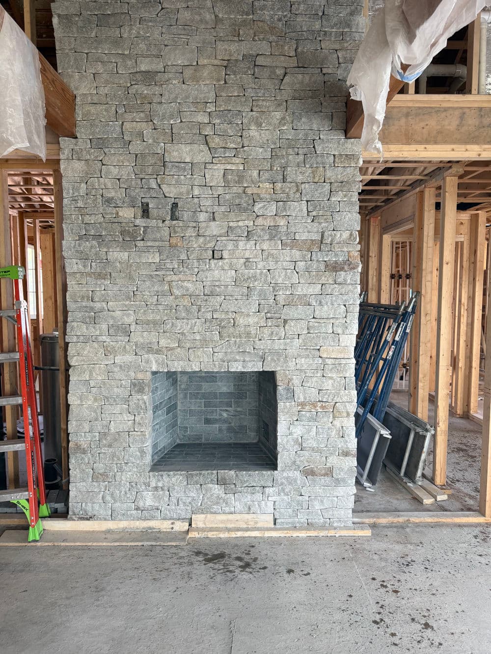 Modern stone fireplace in a newly constructed home, surrounded by wooden framing.