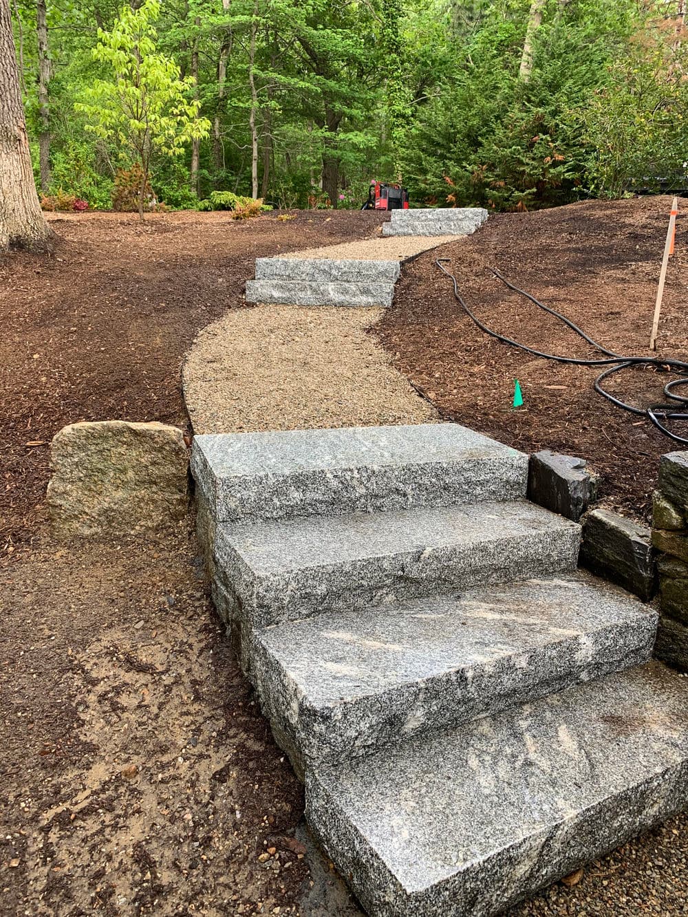 Granite steps leading up a landscaped garden path surrounded by greenery.